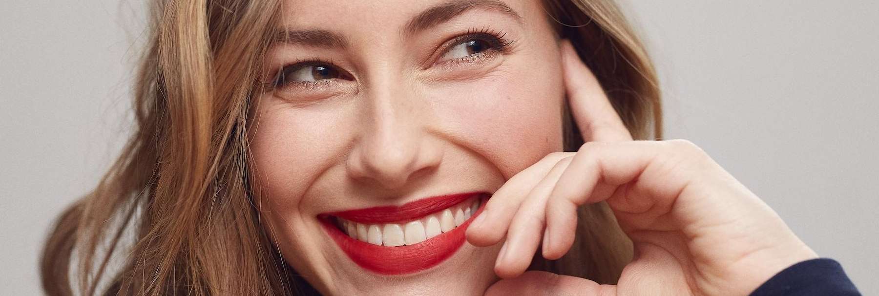 A smiling woman wearing red lipstick, exemplifying the positive impact of cosmetic dentistry on 