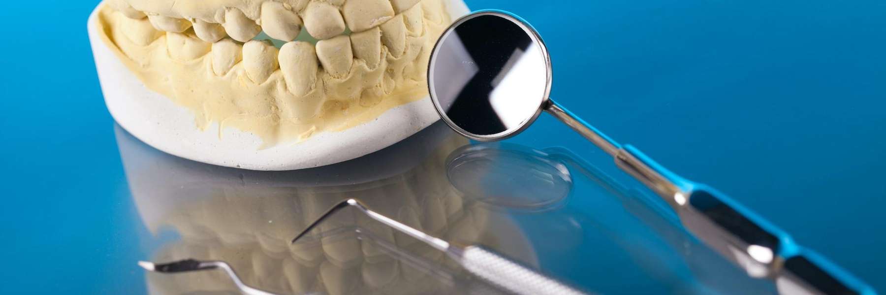 Dental tools arranged beside a model of human teeth.