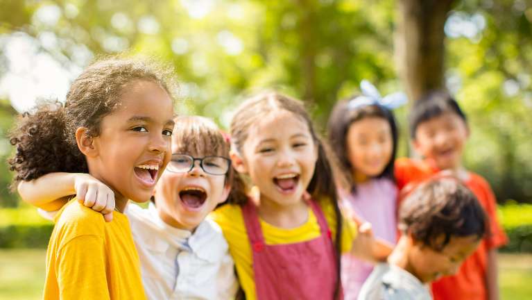 A cheerful group of kids in a park, laughing and smiling, showcasing the joy of childhood