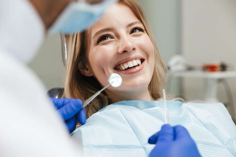 A woman smiling and chatting with her dentist after completing a dental filling procedure.
